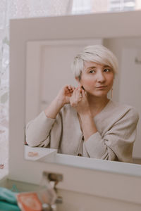 Portrait of woman holding camera at home