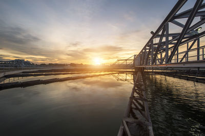 Bridge over river against sky during sunset