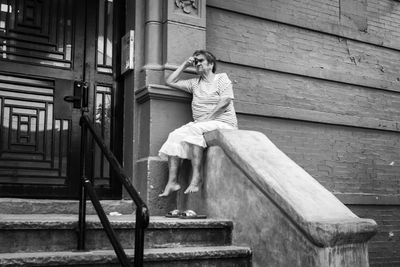 Portrait of young woman sitting on staircase of building