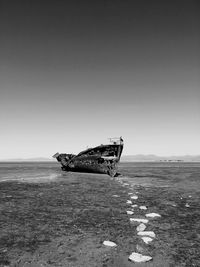 Abandoned boat on beach against sky