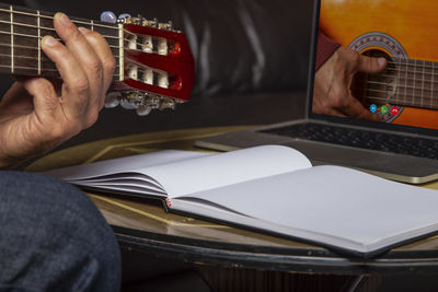 Midsection of man playing guitar