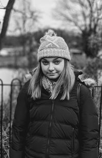 Portrait of young woman standing against trees