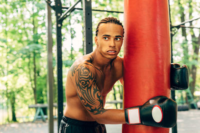 Athlete holding punching bag while standing outdoors