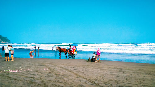 People on beach against clear sky