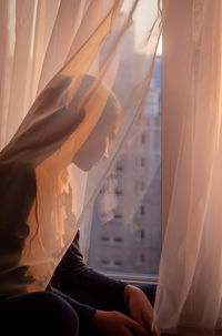 A girl looks out the window at the city landscape at sunset