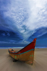 Boat moored on beach against sky