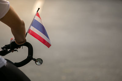 Close-up of hand holding flag against sky