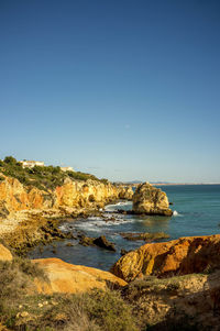 Scenic view of sea and cliff against clear sky