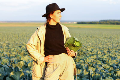 Woman picking cabbage vegetable at field. female farmer working at organic farm. harvesting