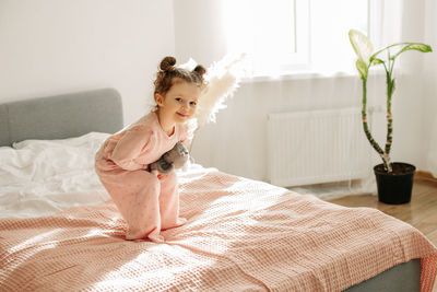 Portrait of young woman sitting on bed at home