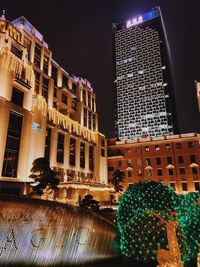 Low angle view of illuminated buildings against sky at night