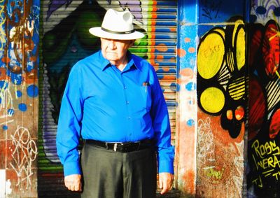 Full length of young man standing against graffiti wall