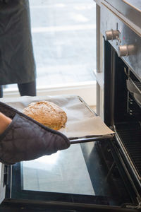 Cropped hand putting bread in oven