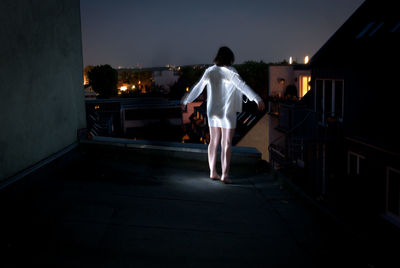 Rear view of man standing on footpath at night