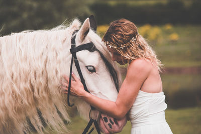 Young woman touching horse