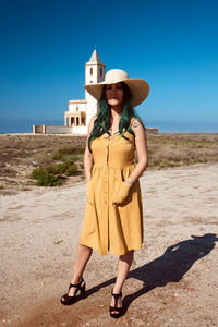 A young girl posing in a hat in the desert with a church in the background. lifestyle concept