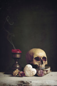 Human skull and candle with flowers on table