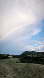 Scenic view of rainbow over field against sky