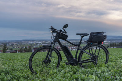 Bicycle parked on field against sky