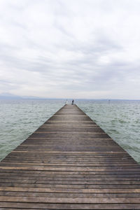 Wooden pier over sea against sky