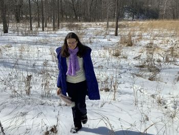 Portrait of young woman standing on snow covered field