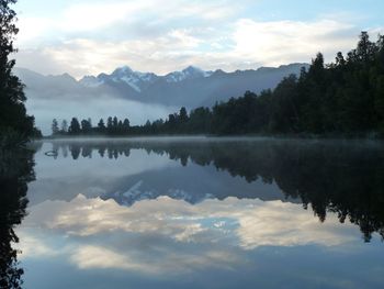 Scenic view of lake by trees against sky