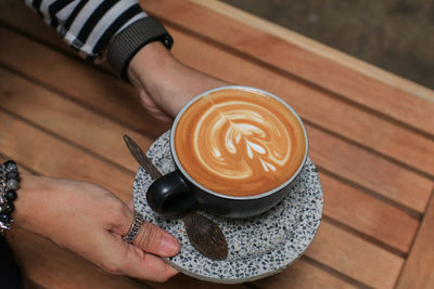 Cropped hand of woman holding coffee on table