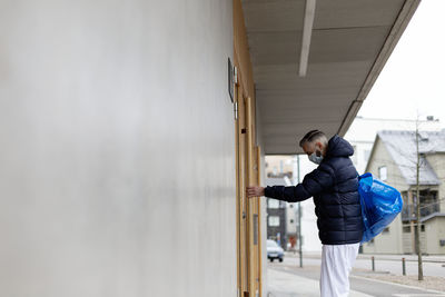 Man wearing face mask opening door