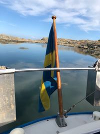 Swedish flag on sailboats in lake against blue sky