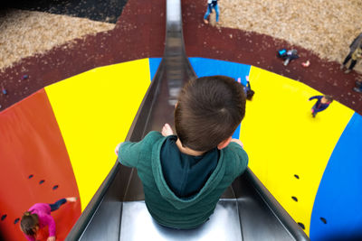 High angle view of boy sitting on multi colored umbrella