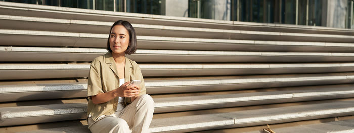 Portrait of young woman standing against wooden wall