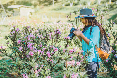 Side view of woman with pink flowers against plants