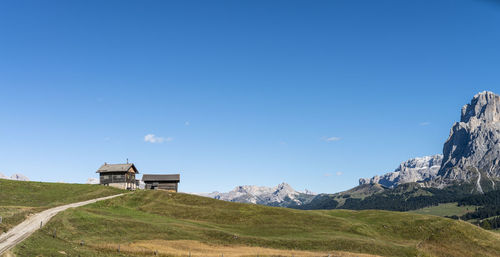 Built structure on land by mountain against clear blue sky