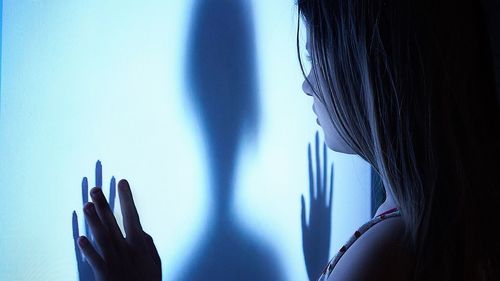 Close-up of girl touching shadow on frosted glass
