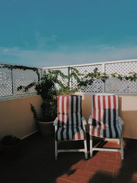 Empty chairs against calm blue sea