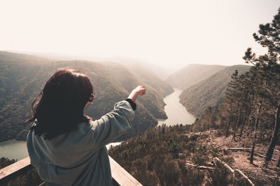 Rear view of man looking at mountain range against sky