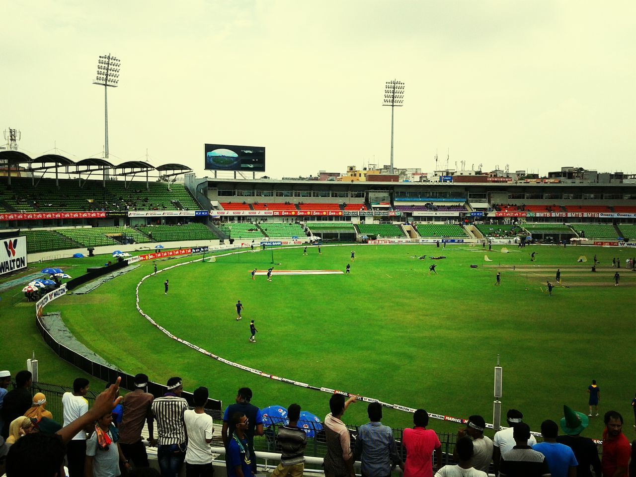 large group of people, men, grass, sport, leisure activity, lifestyles, person, crowd, green color, stadium, field, soccer, high angle view, sky, competition, playing field, landscape, spectator, mixed age range