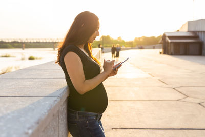 Side view of woman standing on mobile phone