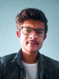 Portrait of young man wearing eyeglasses against white background