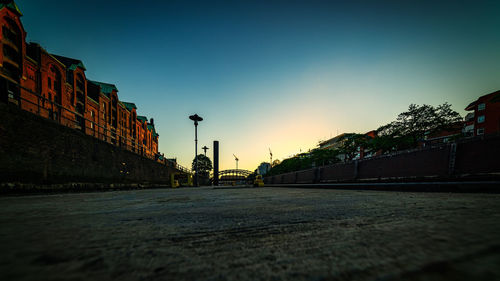 Surface level of road against buildings at sunset