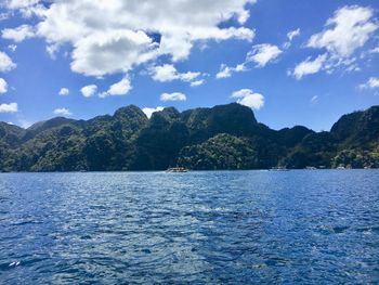 Scenic view of sea and mountains against blue sky