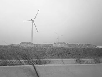 Wind turbines on land against clear sky