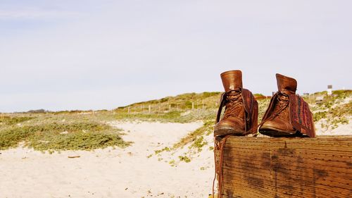 Low section of shoes on beach against clear sky