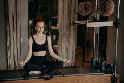 Full length of woman meditating at gym