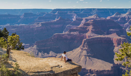 High angle view of man sitting on cliff against canyon