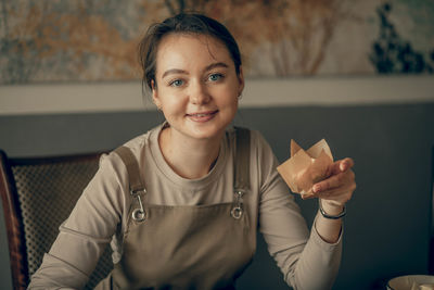 Young baker holding freshly made cupcake, satisfaction of creating sweet delights in a cozy kitchen