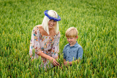 Mother with son standing on agricultural field against sky