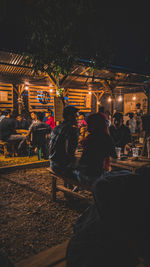 People sitting on illuminated street in city at night