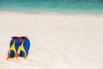 Pair of sandals with sunglasses on sand at beach