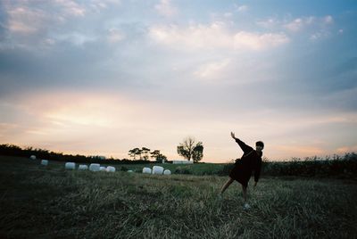 Grass on grassy field against cloudy sky at sunset